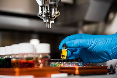 gloved hand holding liquid in vial